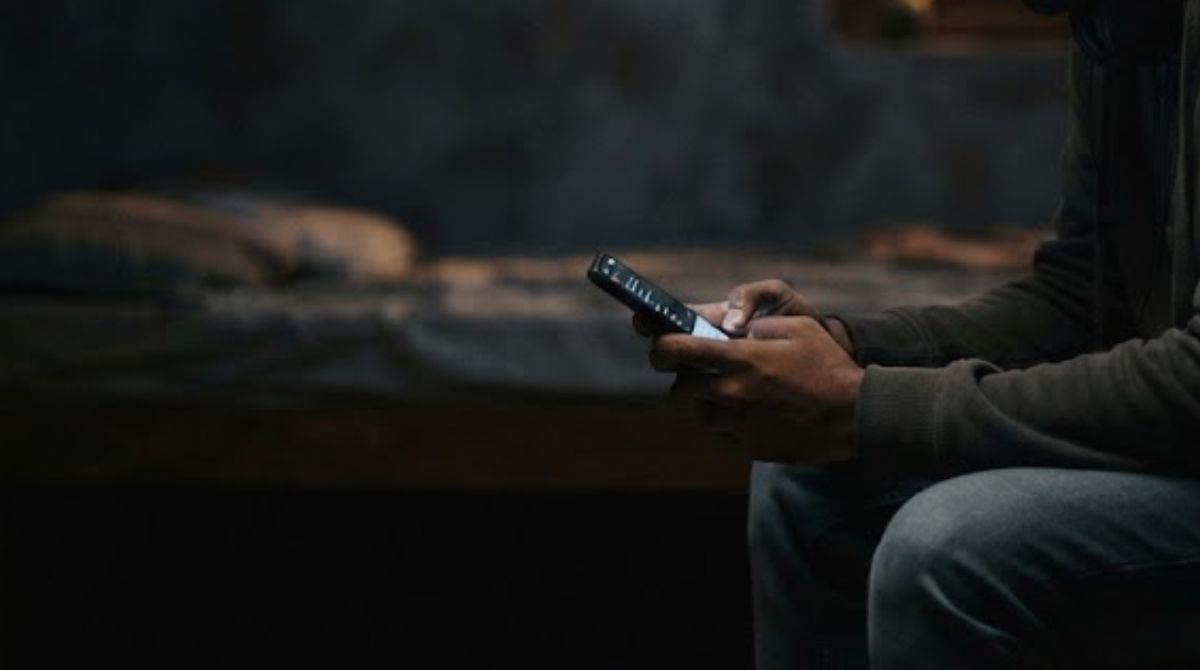 A child looks at a mobile phone screen in the dark, France's social media ban news